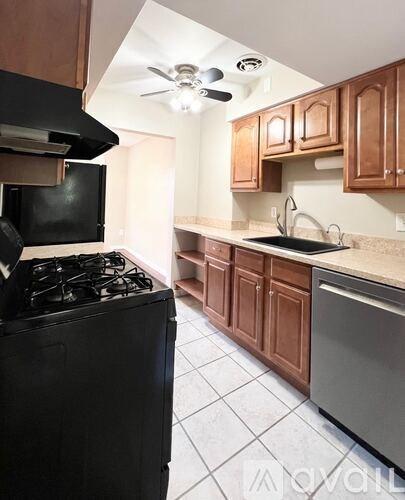 A kitchen with a black stove top oven and wooden cabinets.