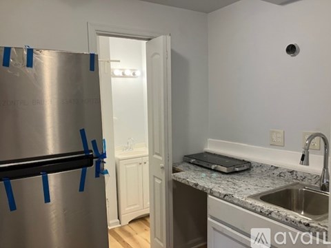 A kitchen with a stainless steel refrigerator covered in blue tape.
