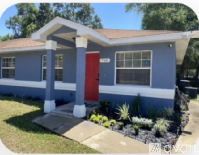 A blue house with a red door and a brown roof.