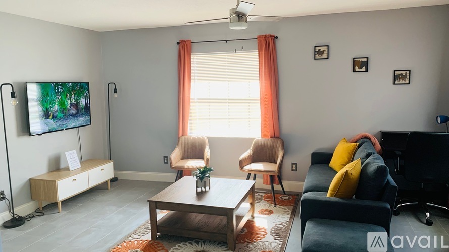 A living room with a flat screen TV, a sofa, a chair, and a coffee table.