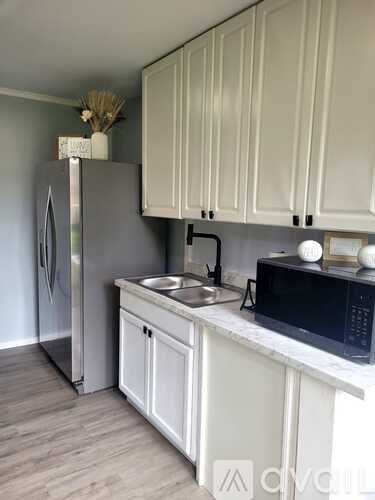 A kitchen with white cabinets and a stainless steel refrigerator.