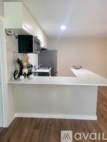 A kitchen with white cabinets and a stainless steel refrigerator.