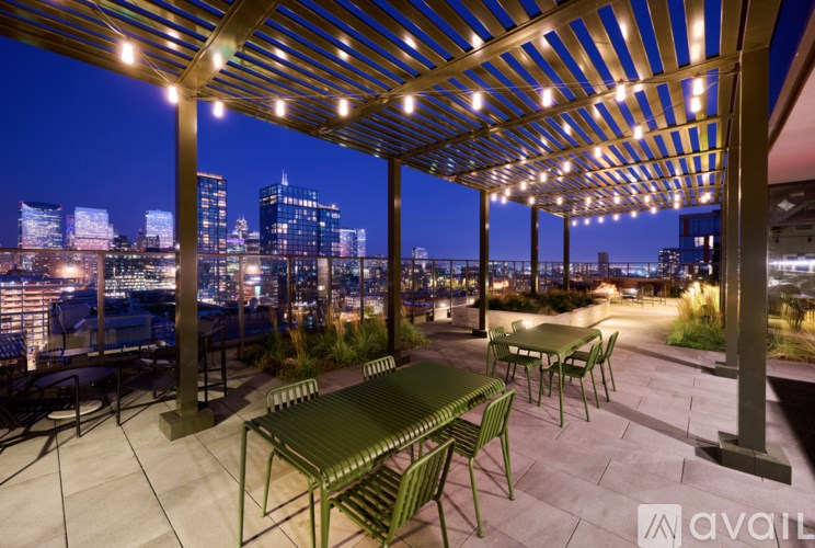A patio with a table and chairs overlooking a city skyline at night.
