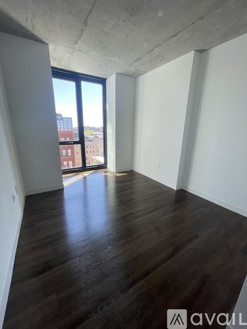 A room with wooden floors and a large window overlooking a cityscape.