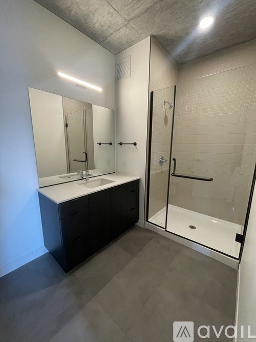 A bathroom with a sink, mirror, and shower.