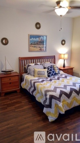 A bedroom with a bed, a nightstand with a lamp, and a painting on the wall.