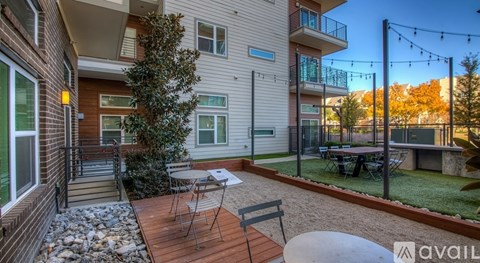 A balcony with a table and chairs is attached to a house.