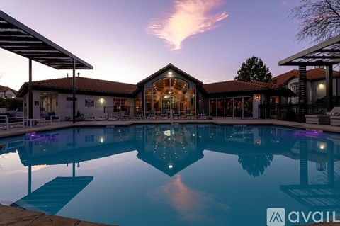 A large swimming pool in front of a house with a sunset in the background.