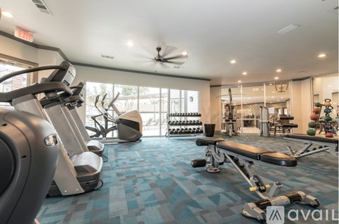 A gym with a variety of equipment including treadmills, weights, and a ceiling fan.