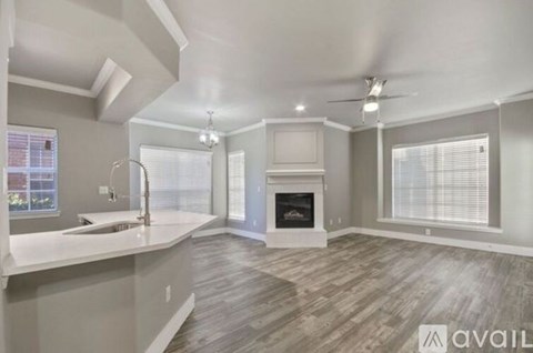A spacious living room with a fireplace and a kitchen area with a sink.