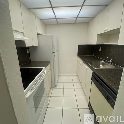 A kitchen with white cabinets and black countertops.
