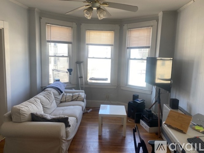 A living room with a white couch and a ceiling fan.
