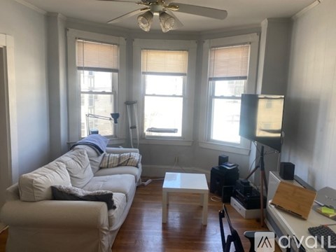 A living room with a white couch and a ceiling fan.