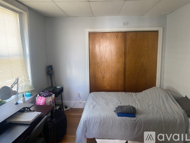 A bedroom with a bed, desk, and window.