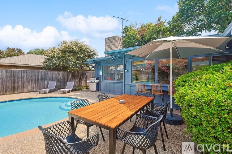 A wooden table is surrounded by chairs on a patio.