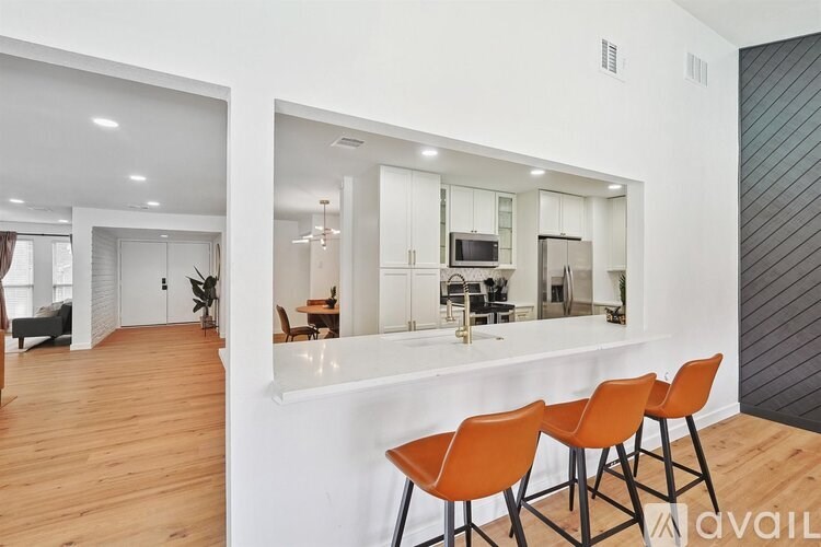 A modern kitchen with a bar area and orange chairs.