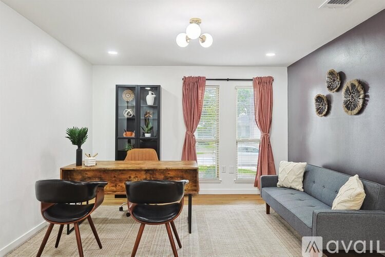 A living room with a grey couch, a wooden table, and a window with red curtains.