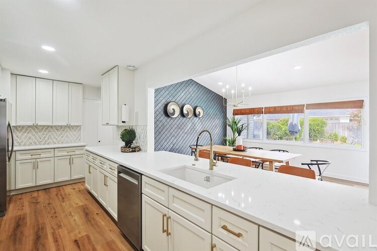 A modern kitchen with white cabinets and a dark blue backsplash.