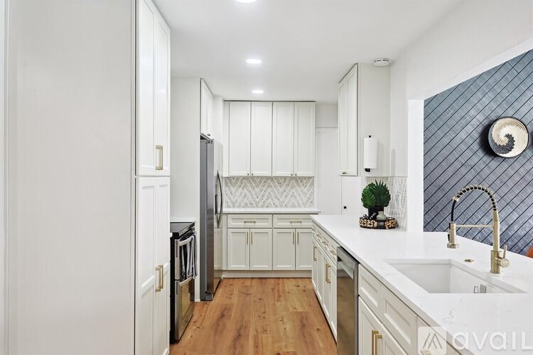 A kitchen with white cabinets and a wooden floor.