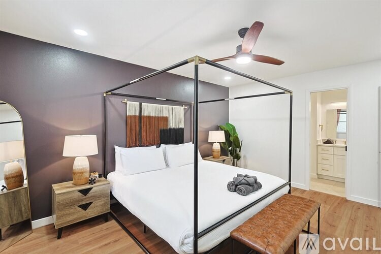 A bedroom with a four poster bed and a wooden bench.