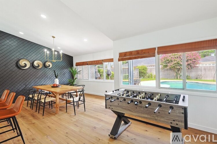A foosball table is in the middle of a room with a wooden table and chairs.