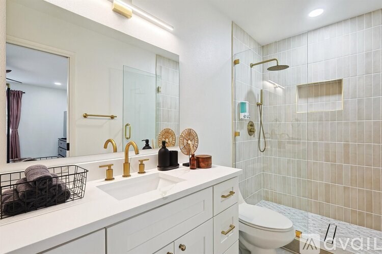 A white bathroom with a sink, mirror, and toilet.