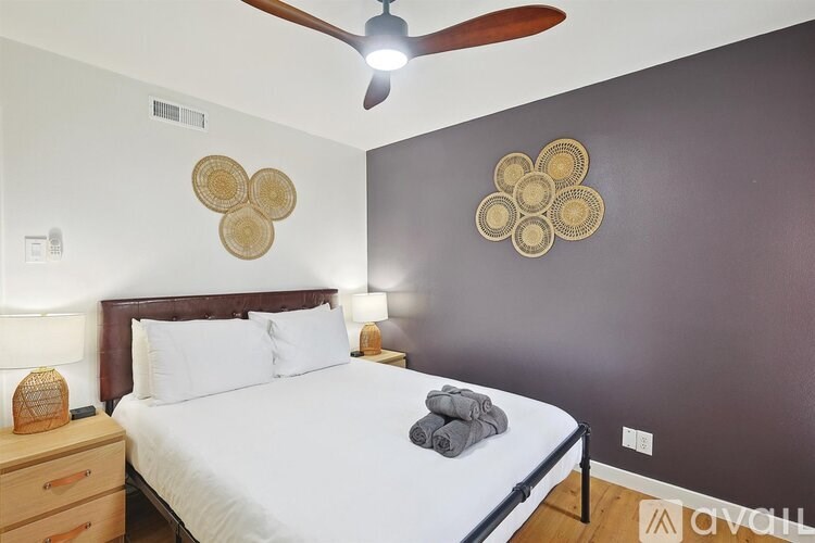 A bedroom with a bed, a ceiling fan, and two wall decorations.