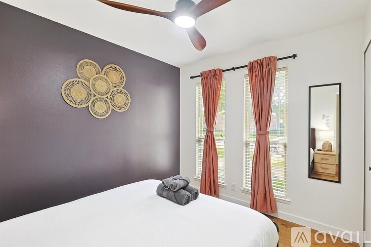 A bedroom with a bed, a ceiling fan, and a mirror.