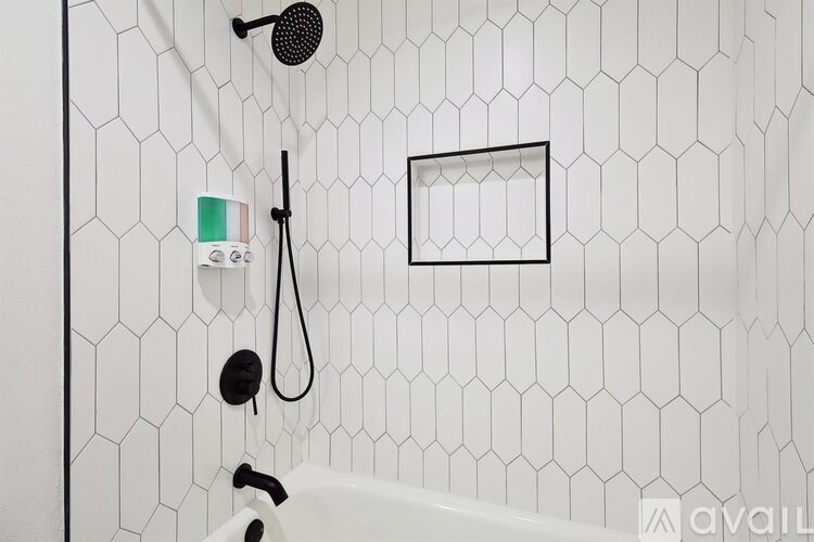 A white tiled shower with a black shower head and hand held shower.