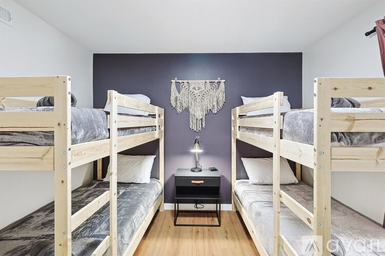 Three bunk beds in a room with a chandelier hanging from the ceiling.