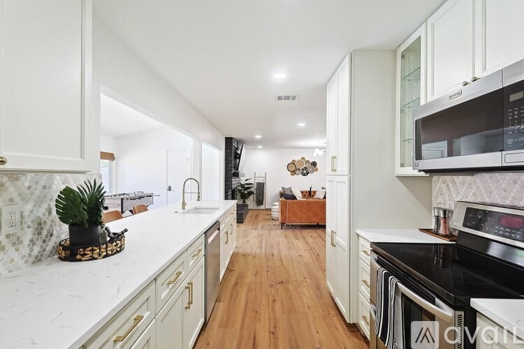 A kitchen with white cabinets and a wooden floor.