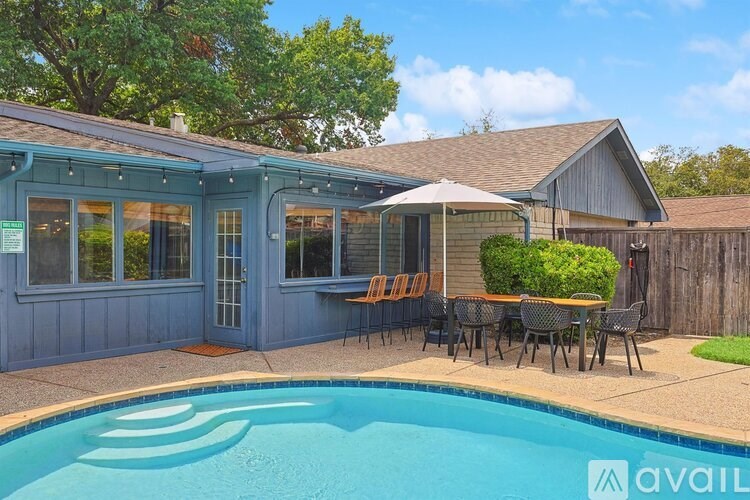 A pool in a backyard with a table and chairs.