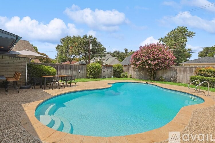 A small residential pool surrounded by a gravel patio and a wooden fence.