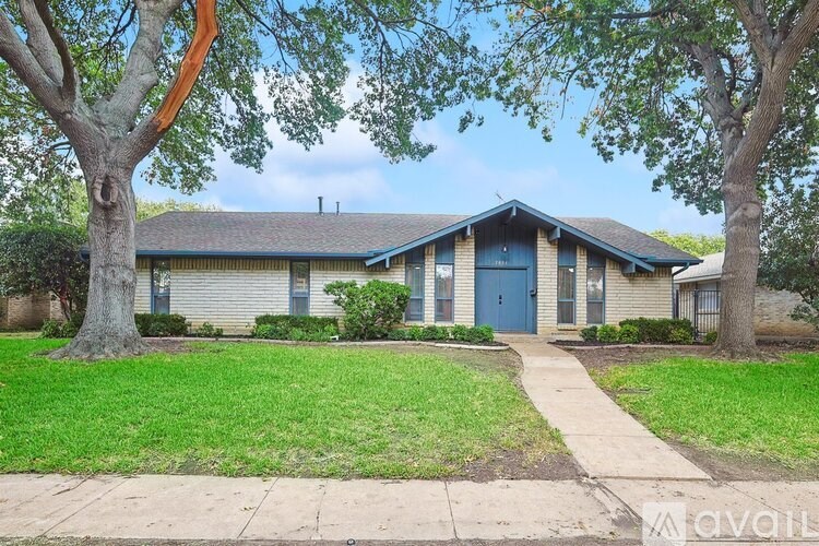 A house with a blue door is surrounded by green grass and trees.