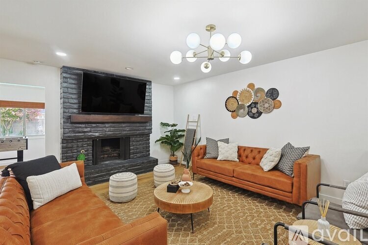 A living room with a brown couch, a fireplace, and a TV mounted above it.