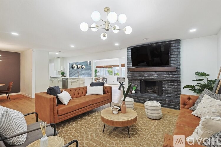 A living room with a brown couch, a fireplace, and a television.