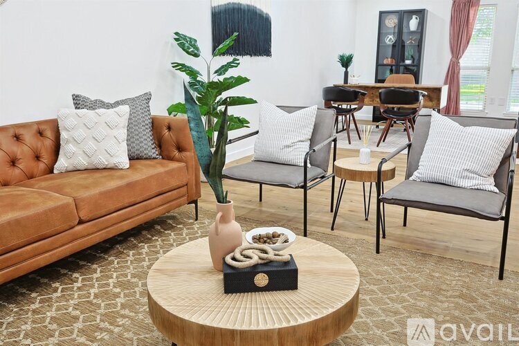 A living room with a brown sofa, grey chairs, and a wooden coffee table.