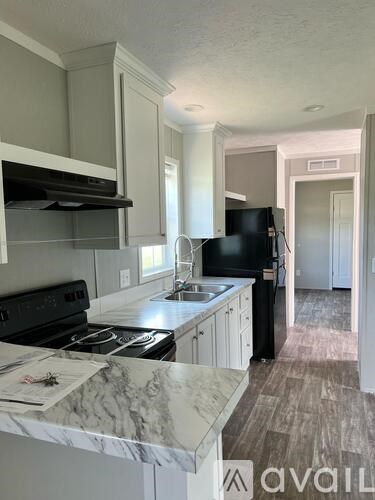 A kitchen with a black fridge and a black stove top oven.