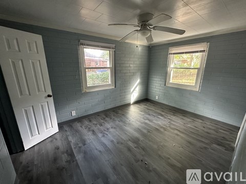 A room with a ceiling fan and two windows.