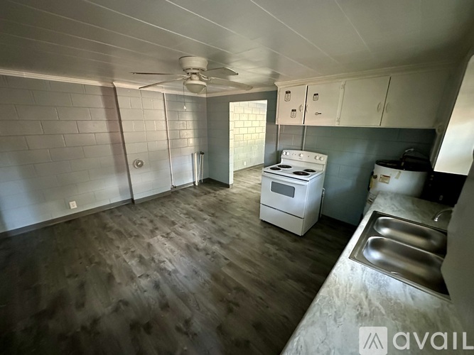 A kitchen with a white stove and wooden floors.