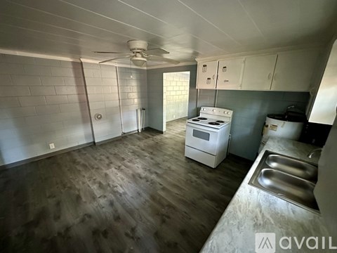 A kitchen with a white stove and wooden floors.