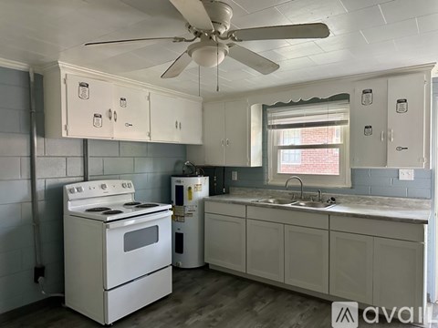 A kitchen with a white stove and a fan on the ceiling.