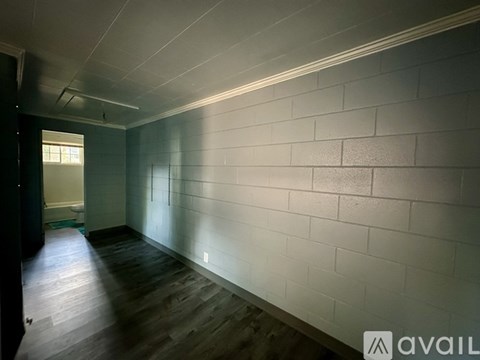A long hallway with a white wall and wooden floor.