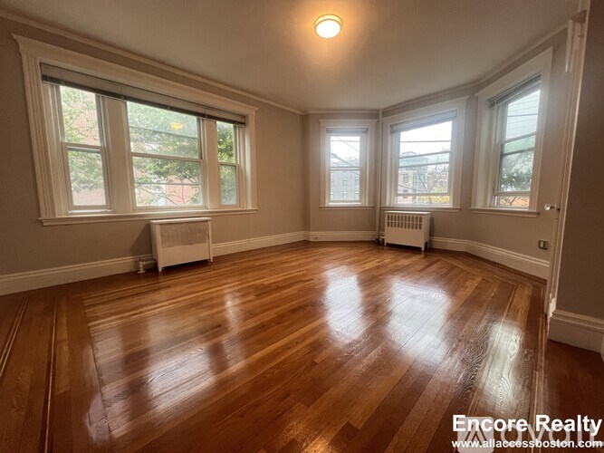 A room with wooden floors and three windows.