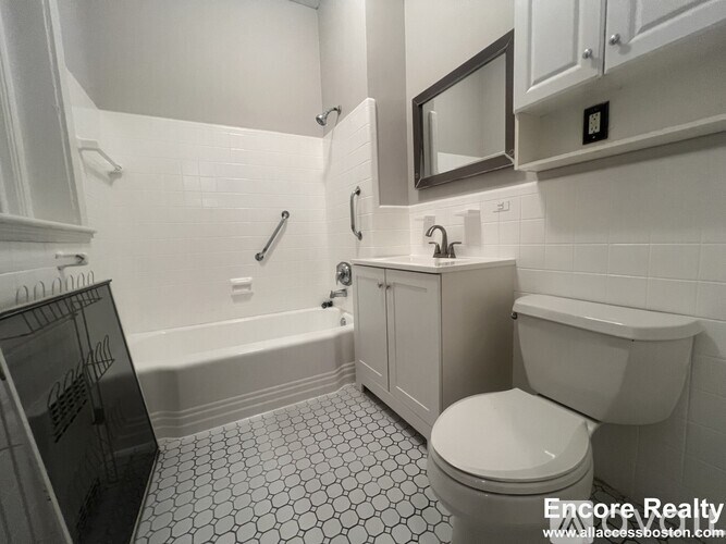 A white bathroom with a toilet, sink, and a mirror.