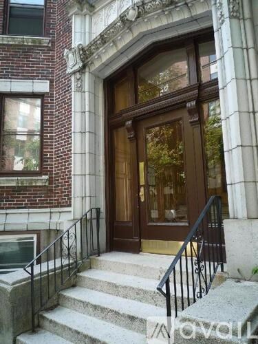 A brown door with a glass window is flanked by two white columns.
