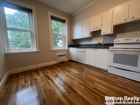 A kitchen with white cabinets and a black stove top oven.