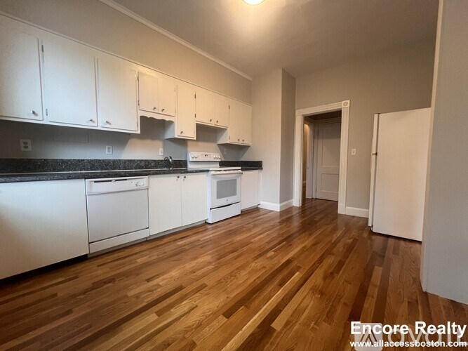 A kitchen with white cabinets and black countertops.