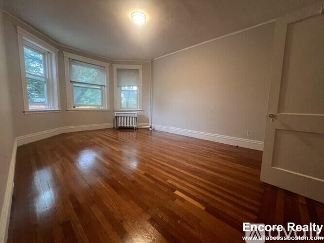 A room with wooden floors and a window with blinds.