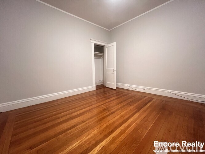 A room with wooden flooring and a doorway leading to another room.